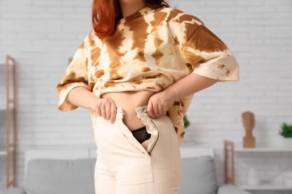 Image of woman trying to do her trousers up after pregnancy weight gain Windsor